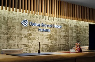 Una reception del Daiwa Roynet Hotel Premier con una parete in listelli di legno e un cartello sopra.
