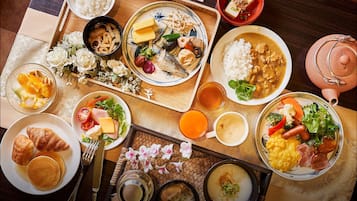 A variety of dishes including rice, soup, and meat, arranged on a wooden table with a woven placemat.