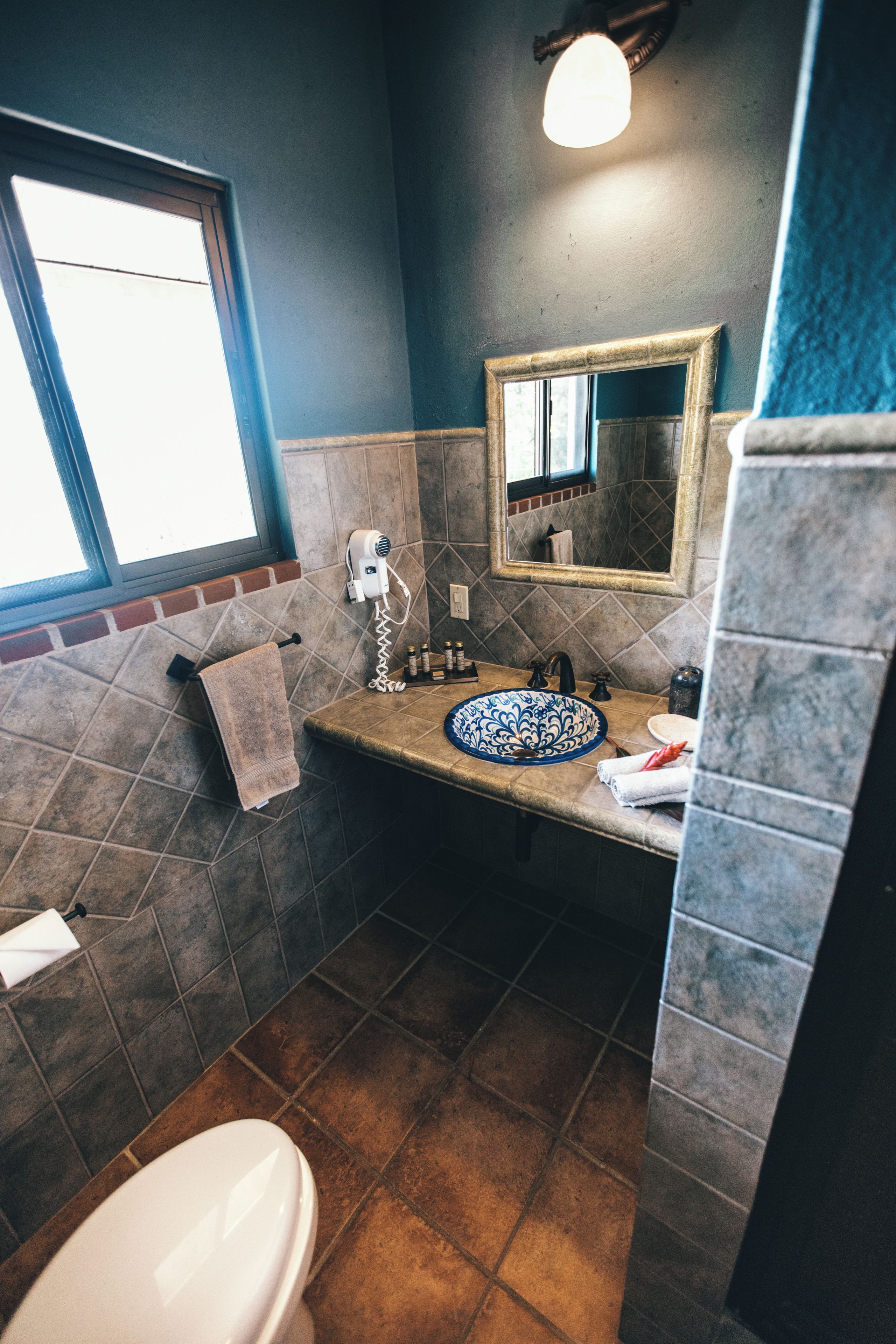 A bathroom with a toilet, sink, and a mirror.