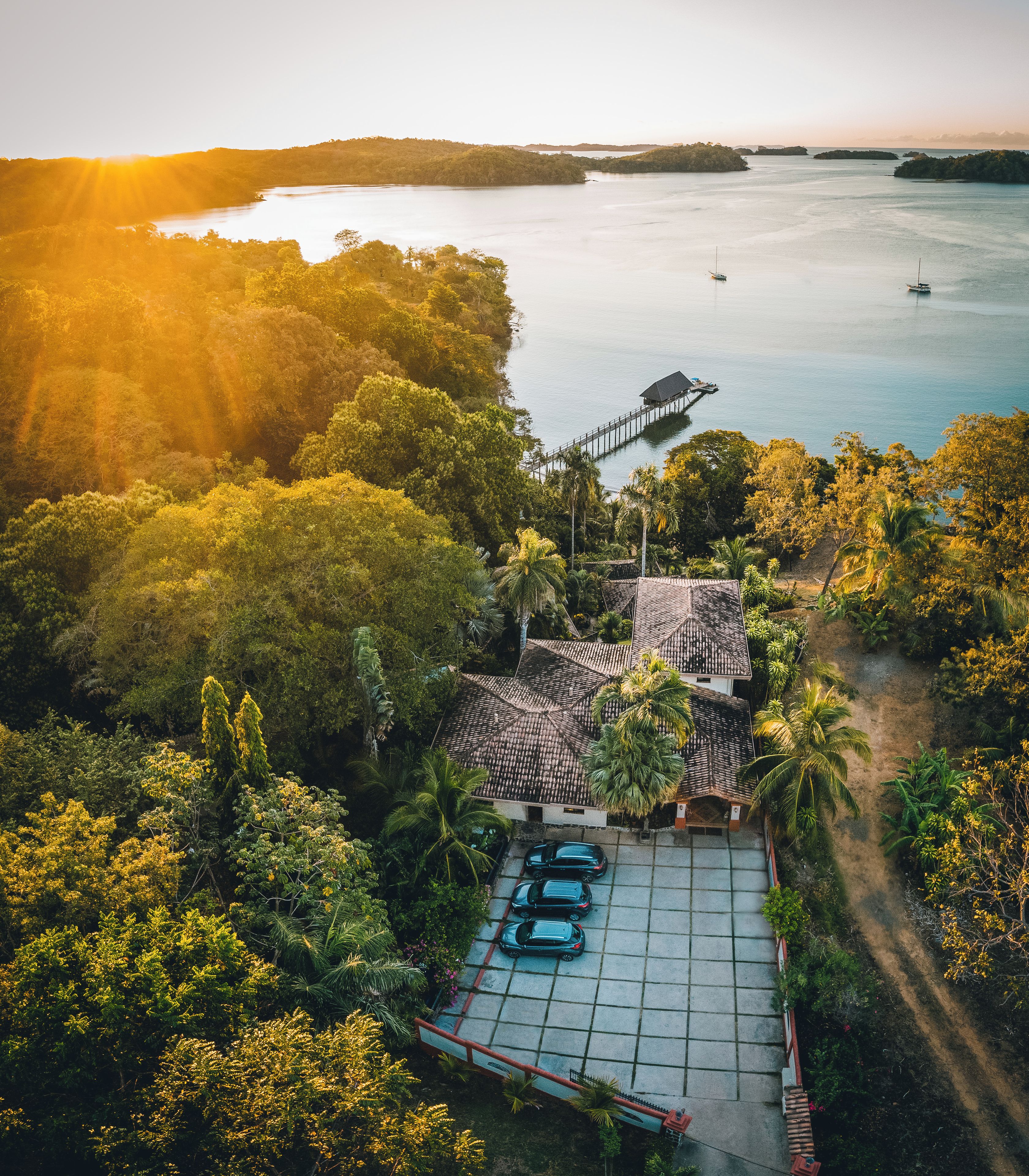 A coastal property with a dock, a parking area, and lush greenery.