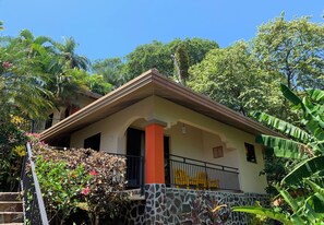 A two-story house with a stone foundation, a balcony with a metal railing, and a staircase leading to the upper floor. - Seagull Cove Resort (Boca Chica)