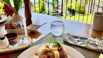 Una mesa con un plato de postre, un vaso de agua y vistas al mar.