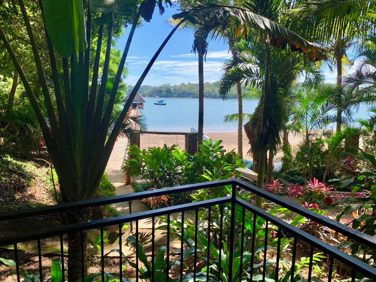 Un balcon avec vue sur une plage et un bateau sur l’eau.