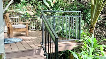 A wooden deck with a metal railing leading to a covered porch area.
