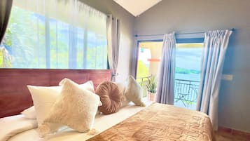 Habitación de hotel con una cama grande, vistas al exterior y un balcón con barandilla.