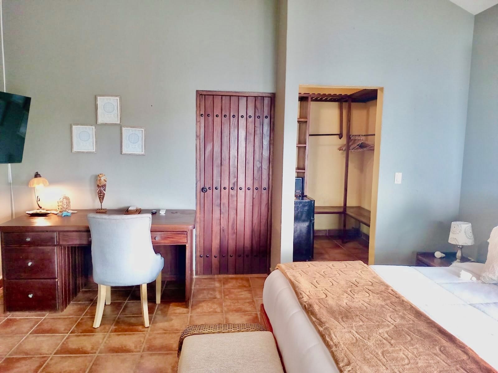 Un dormitorio con cama, escritorio, silla, armario y vestidor.