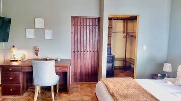 Un dormitorio con cama, escritorio, silla, armario y vestidor.