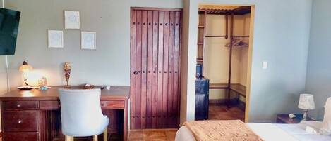 A bedroom with a bed, a desk, a chair, a wardrobe, and a walk-in closet.