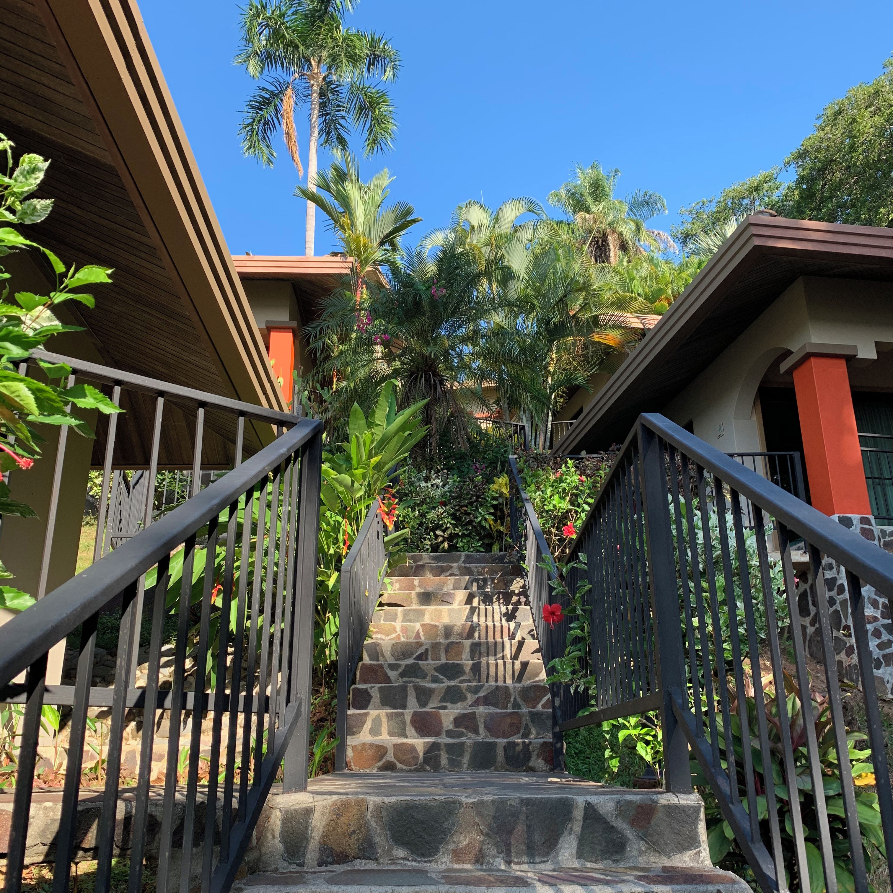 A staircase with stone steps leading to a house with a red roof.
