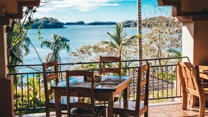 Una terraza con mesa y sillas, con vista a un cuerpo de agua y vegetación.