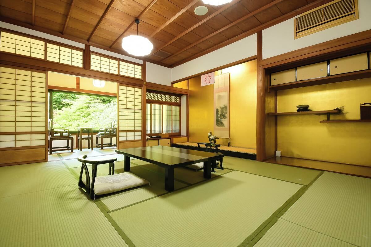 A traditional Japanese room with tatami flooring, a low table, and sliding doors.