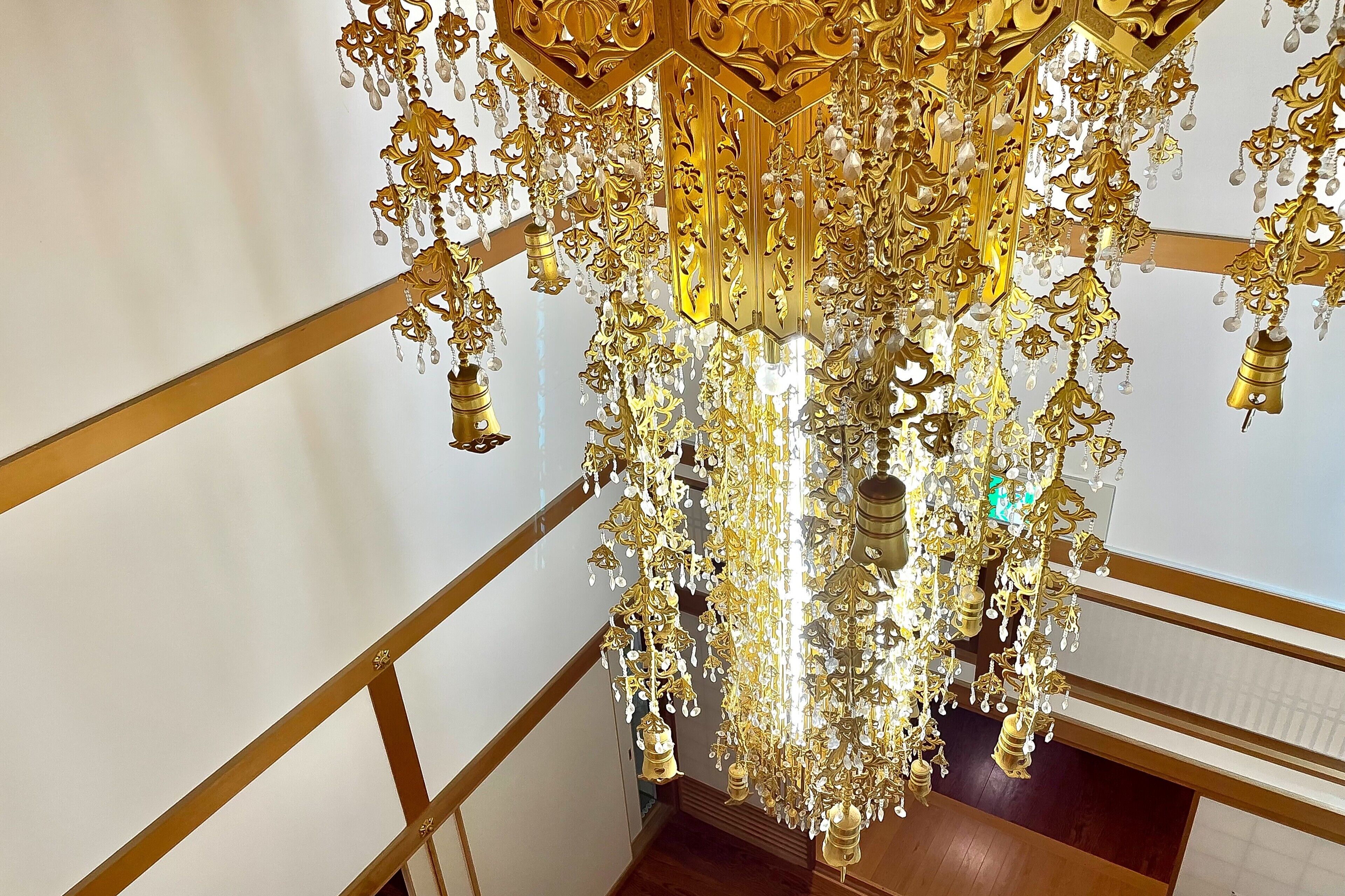 A grand chandelier with intricate golden designs and crystal decorations hanging from the ceiling.