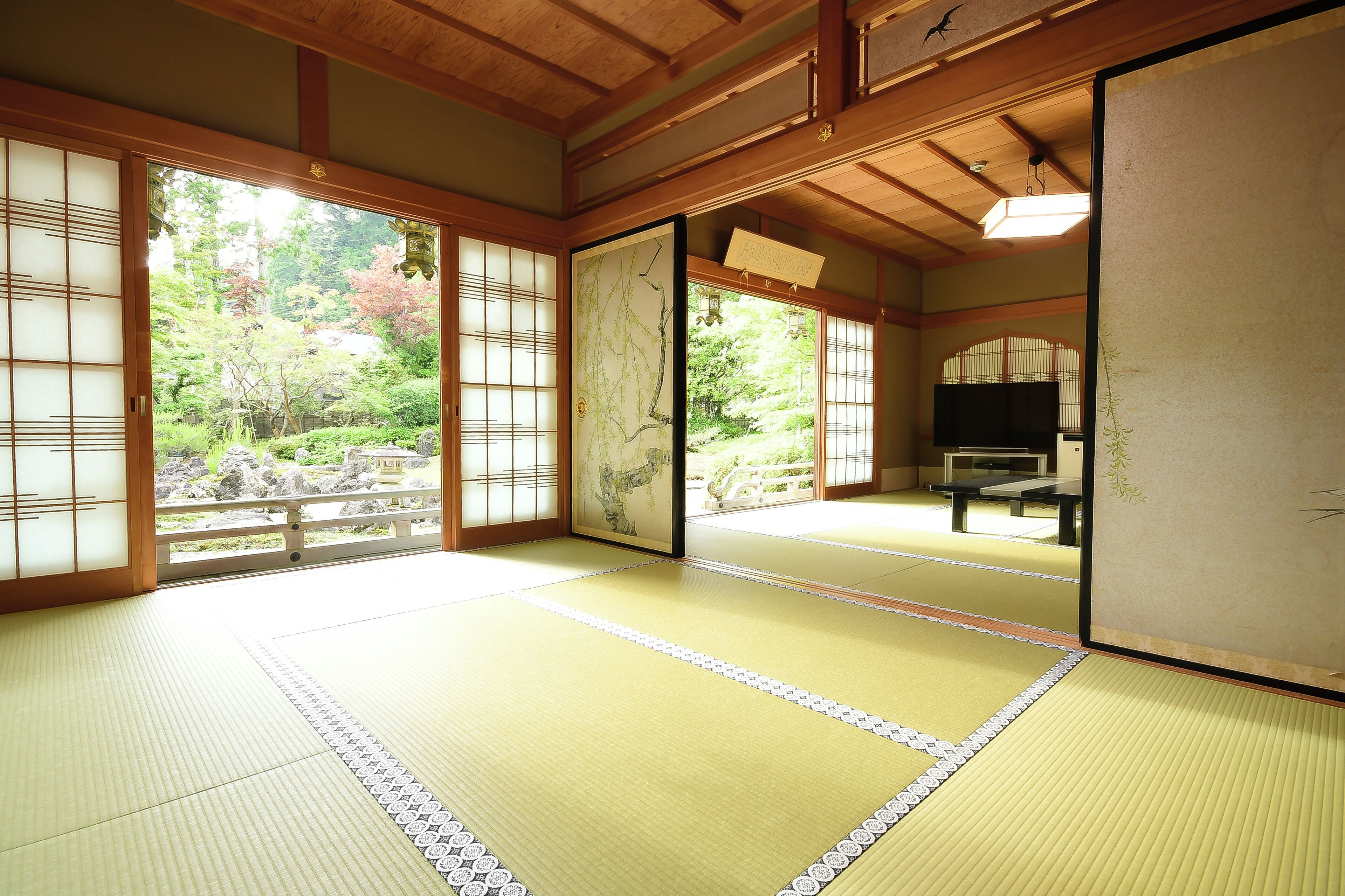 Habitació japonesa tradicional amb tatami, portes corredisses i vista a un jardí.