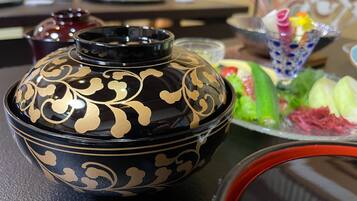 A black and gold decorative bowl on a table with a salad and a glass of bubble tea.