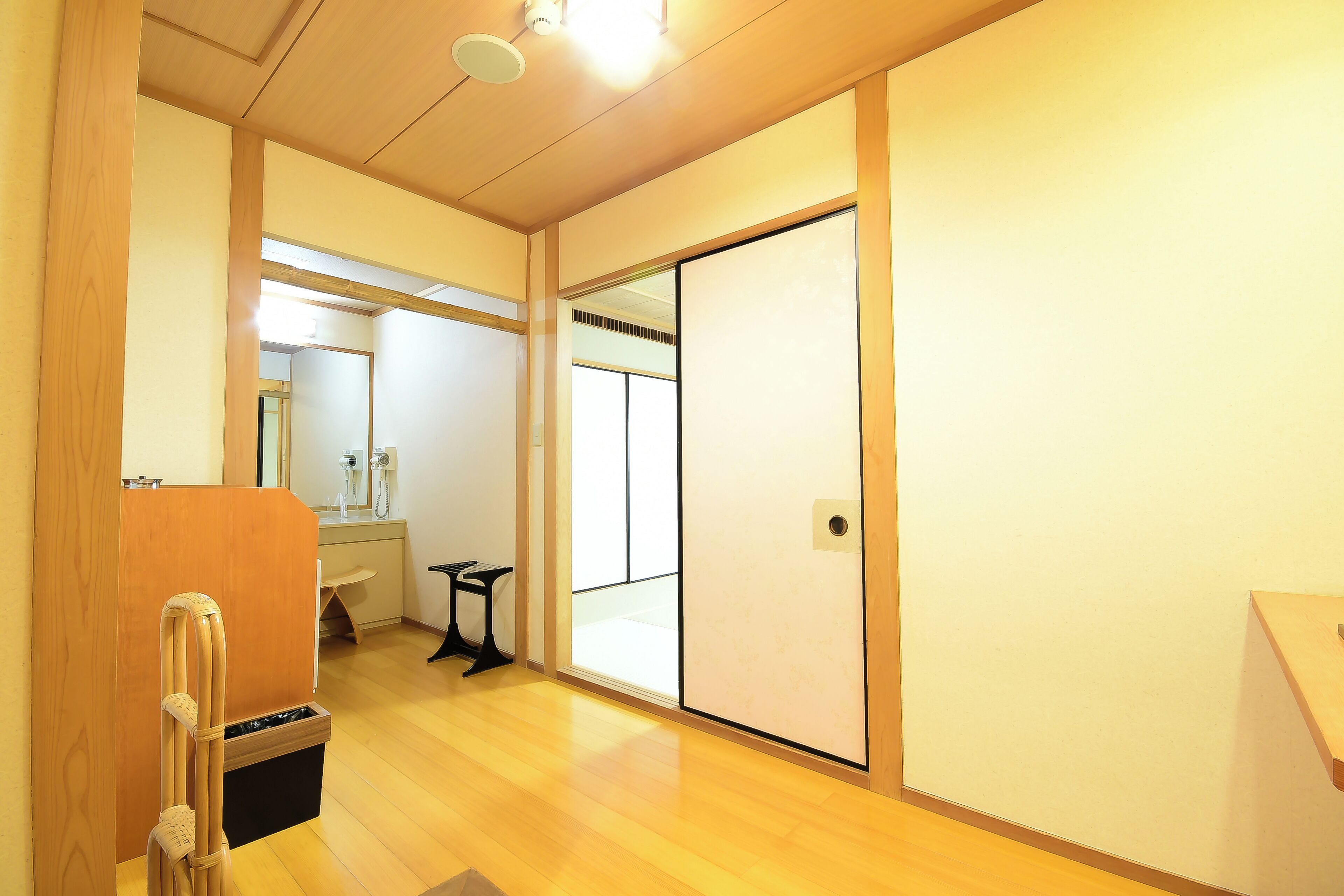 A room with a sliding door, a wooden floor, a small table, and a bench.
