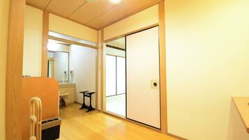 A room with a sliding door, a wooden floor, a small table, and a bench.