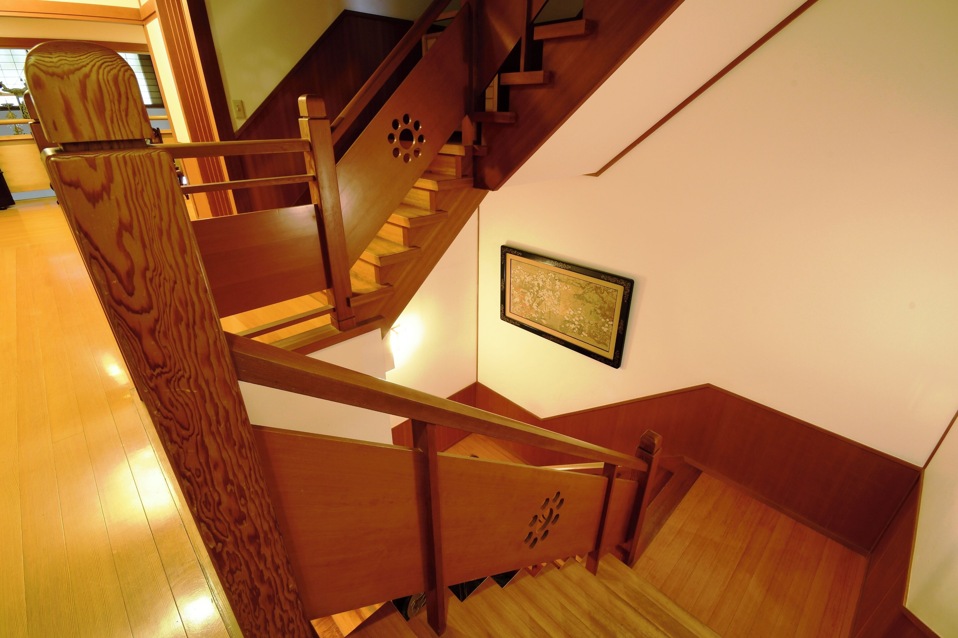 A wooden staircase with a handrail and a picture on the wall.