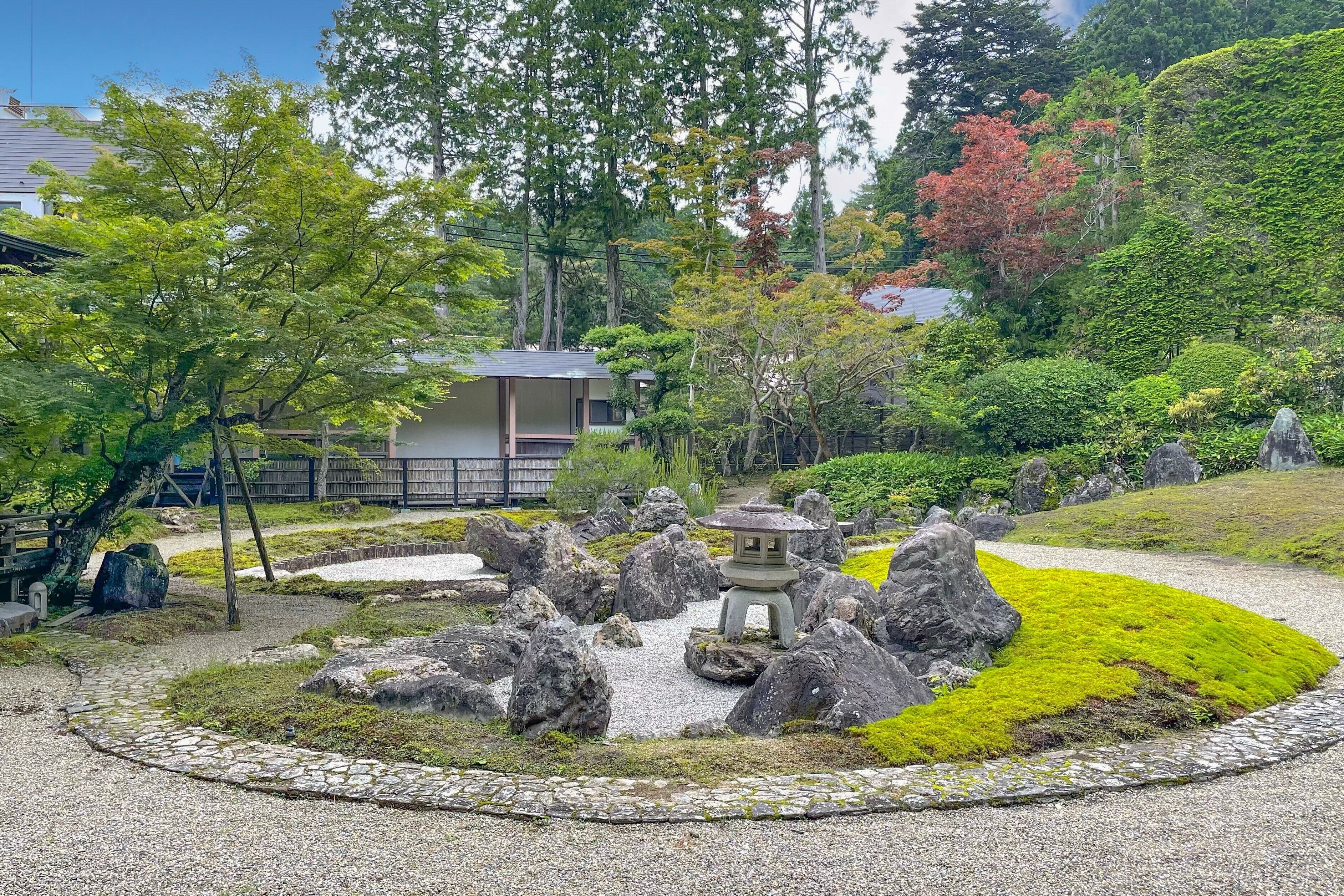 Un jardín japonés tradicional con un farol de piedra, rocas grandes y un sendero.
