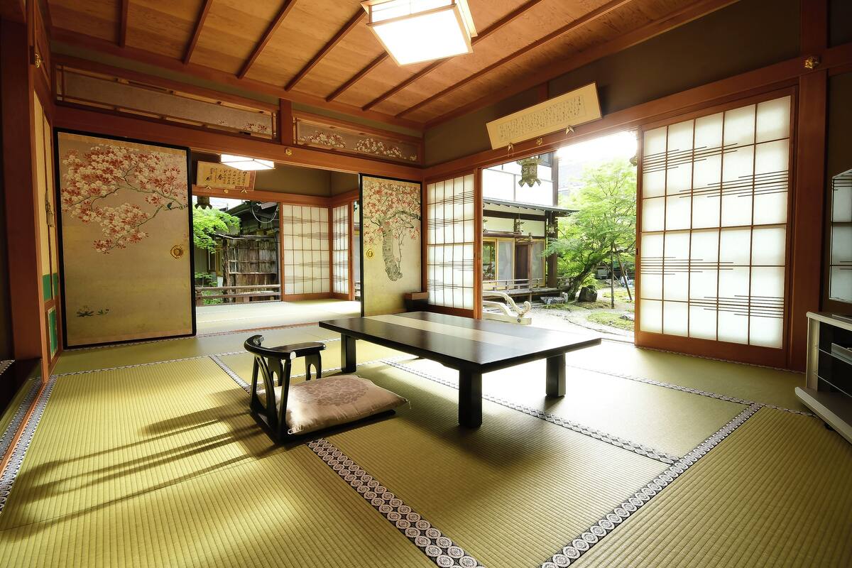 A traditional Japanese room with tatami flooring, a low table, and sliding doors.