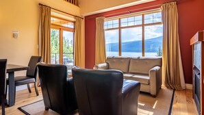 A living room with a sofa, two chairs, a dining table, and a fireplace. - Halcyon Hot Springs Resort (Nakusp)