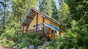 A cabin with a steep staircase, surrounded by dense forest. - Halcyon Hot Springs Resort (Nakusp)