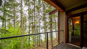 A balcony with a view of tall trees and a body of water. - Halcyon Hot Springs Resort (Nakusp)