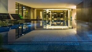Una piscina interior moderna con paredes de vidrio transparente, un suelo limpio y reflectante, y un interior bien iluminado.