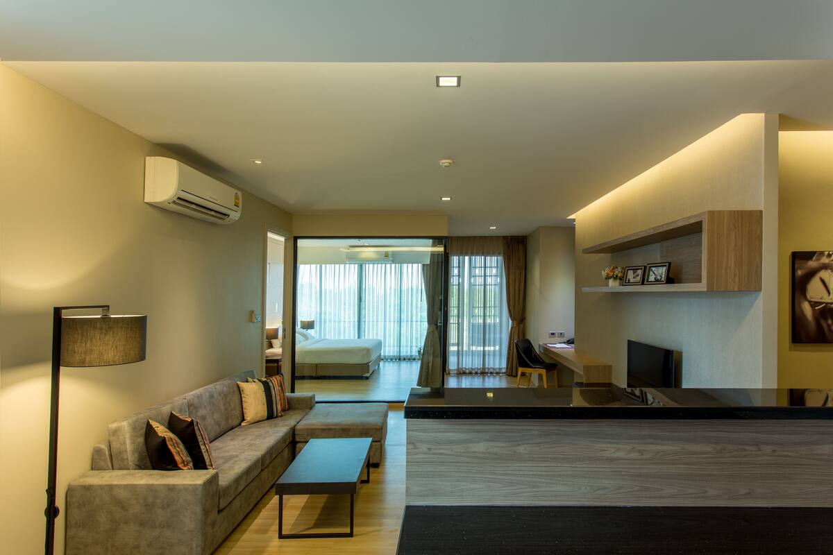 Una sala moderna con sofá, mesa de centro y televisor de pantalla plana. Cuenta con una zona de cocina con encimera y una mesa de comedor.