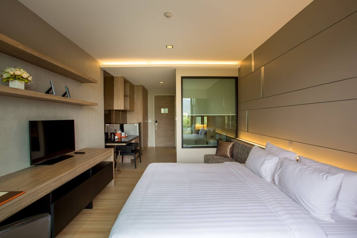 Una habitación de hotel moderna con una cama grande, televisión, escritorio y vistas al exterior.