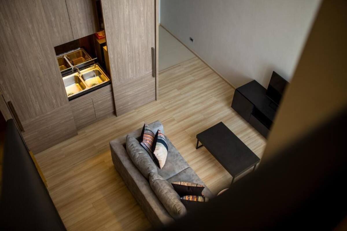 Una sala de estar moderna con cocina integrada, un sofá y un mueble para la televisión.