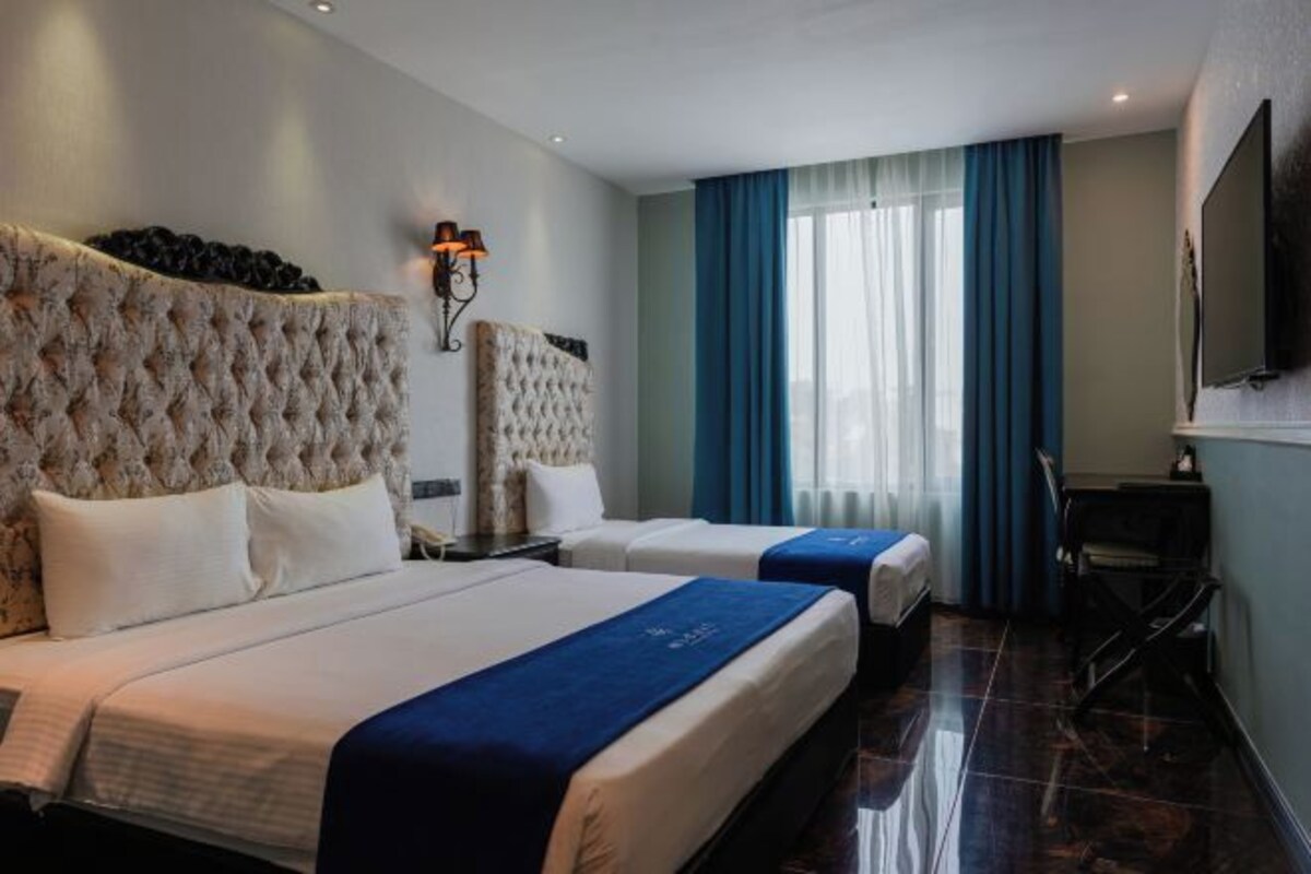 A hotel room with two beds, a flat-screen TV mounted on the wall, and a desk with a chair.