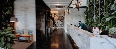 A reception area with a marble counter, a wooden bench, and potted plants.