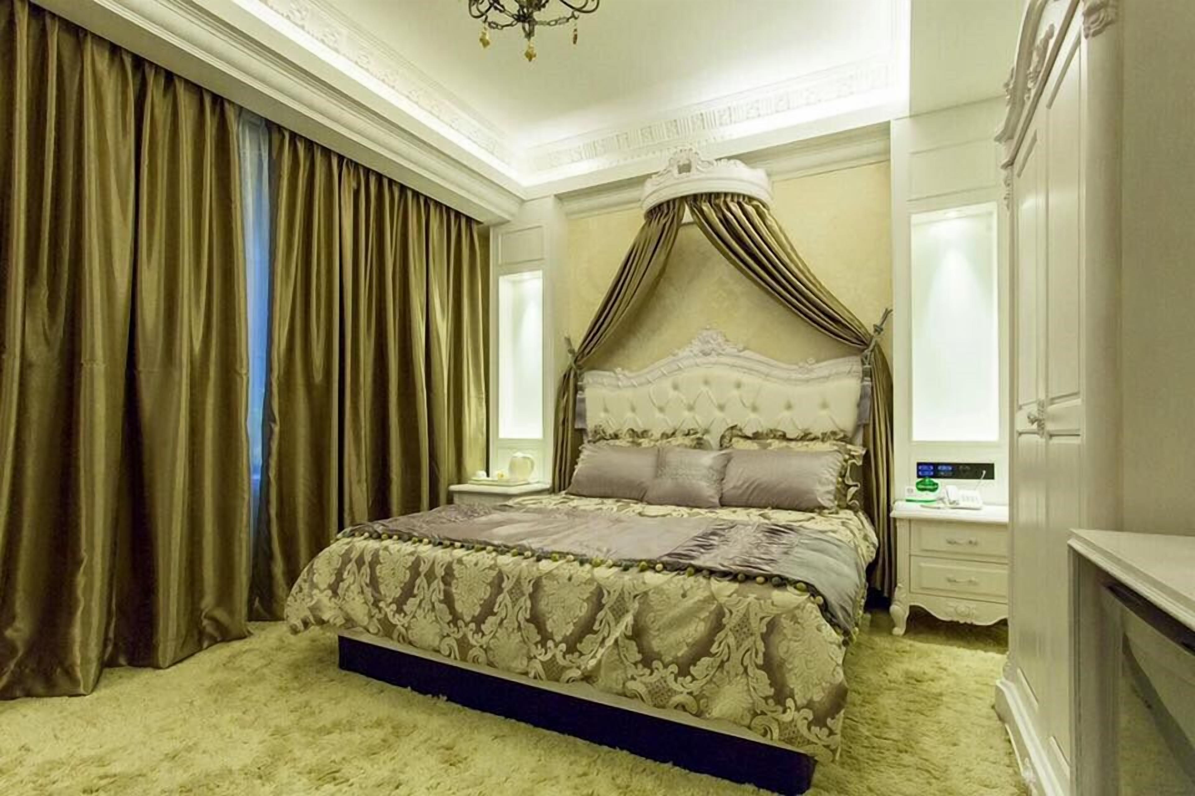 A bedroom with a four-poster bed, a chandelier, and a large window with curtains.