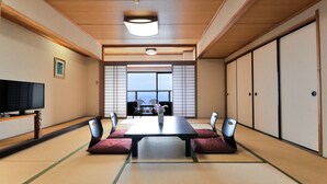 A traditional Japanese room with tatami flooring, a low table, cushions, sliding doors, and a television. - HOTEL KATARA RESORT&SPA (Higashiizu)