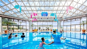 An indoor swimming pool with clear glass ceilings, palm trees, and a blue inflatable float. - HOTEL KATARA RESORT&SPA (Higashiizu)