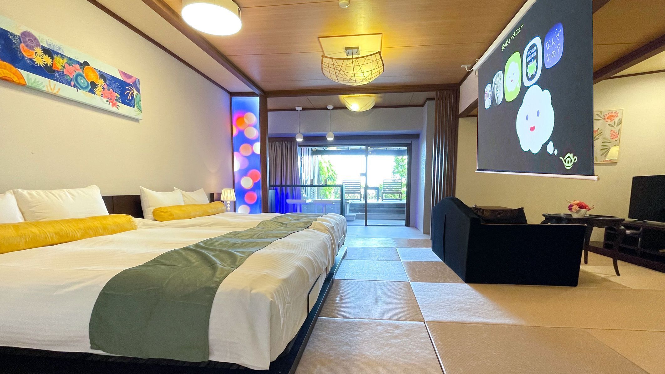 Ein Hotelzimmer mit einem großen Bett, einem Schreibtisch, einem Fernseher und einer Projektionsleinwand.