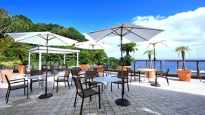 An outdoor patio with tables and chairs, large umbrellas, and potted plants. - HOTEL KATARA RESORT&SPA (Higashiizu)