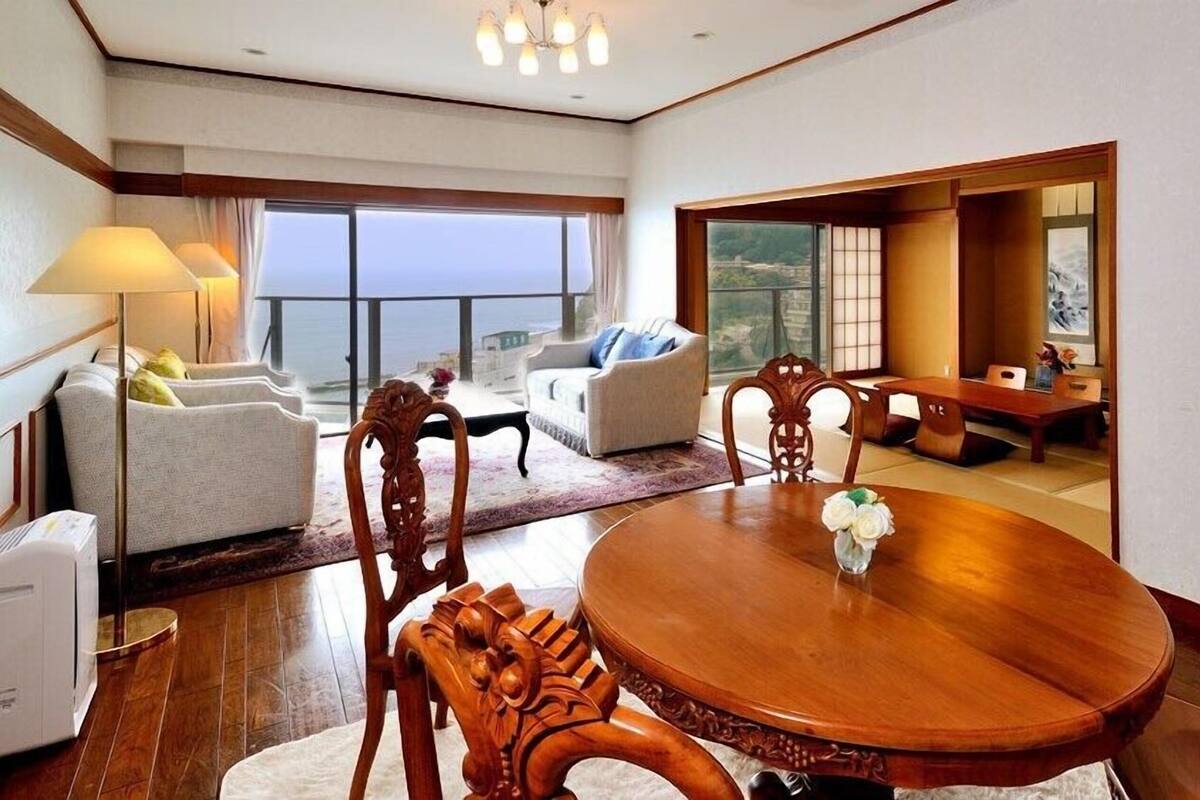 A spacious room with a round wooden dining table, two sofas, and a view of the outdoors.
