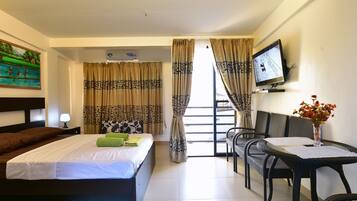 Relax in a spacious room with a large bed, television, and a small table with a vase of flowers.