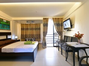 Ein Hotelzimmer mit Bett, Schreibtisch mit Stuhl, Fernseher und Vorhängen.