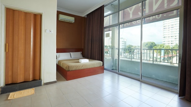 A hotel room with a large sliding glass door to the outside, a bed with a wooden headboard, and a small air conditioning unit on the wall. - Gurney Inn (George Town)
