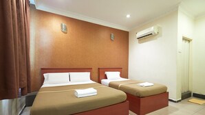 A hotel room with two beds, a wall-mounted air conditioner, and a door. - Gurney Inn (George Town)