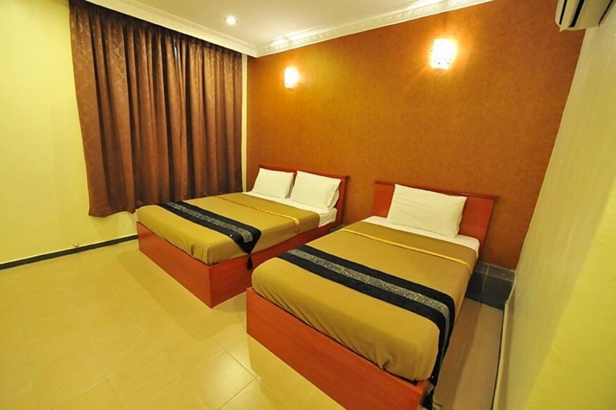 Quarto de hotel com duas camas, uma cortina e um luminário na parede.
