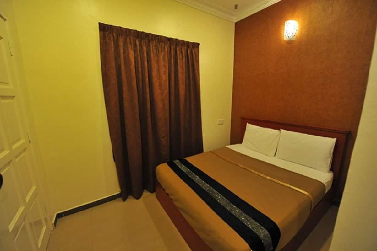 Quarto de hotel com cama, cortinas e luminária fixada na parede.