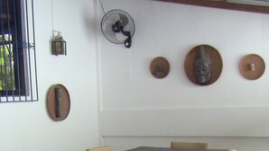 A conference room with a rectangular table, six beige chairs, a standing fan, and three decorative plates on the wall. - Roger's Place Gay Guesthouse - Caters to Gay Men (Boracay Island)