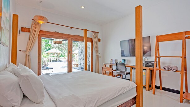 A bedroom with a bed, a desk, a chair, a television, and a view of the outdoors.