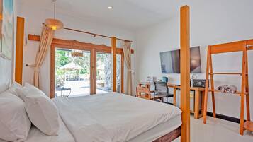 A bedroom with a bed, a desk, a chair, a television, and a view of the outdoors.