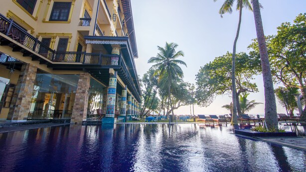 Un hotel con piscina, palmeras y vista al océano.