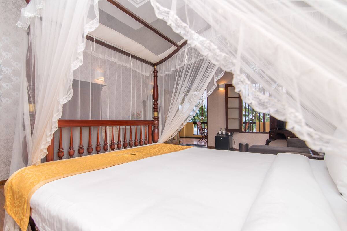 A bed with a canopy, a wooden headboard, and a yellow bedspread.
