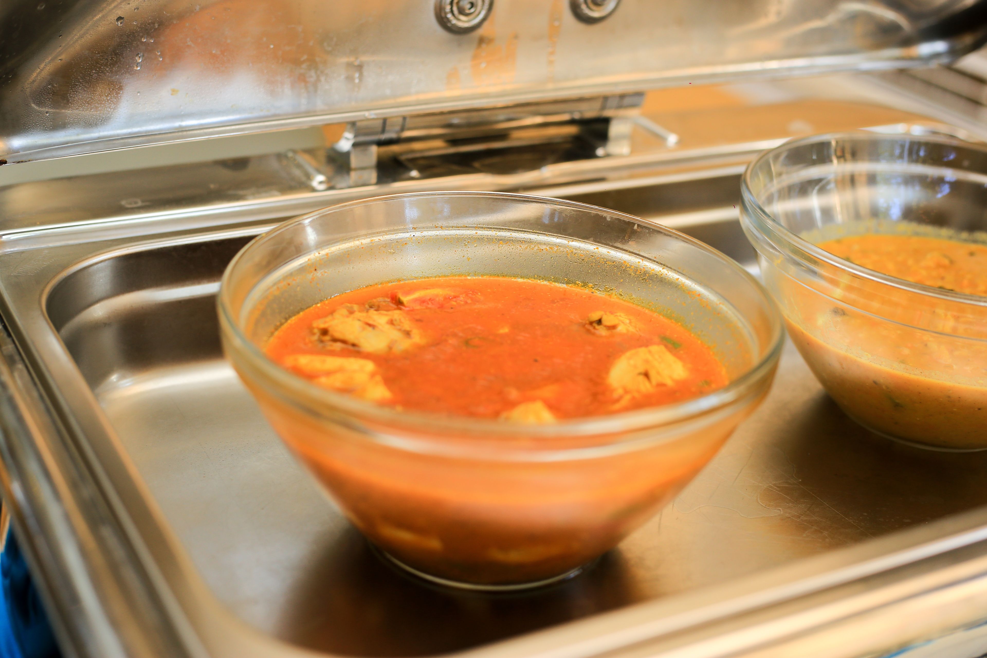 Two glass bowls of soup on a stainless steel tray.